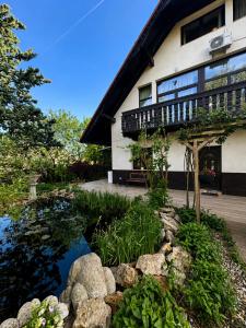 a house with a pond in front of a building at Határtalan Vendégház in Pilisszentiván