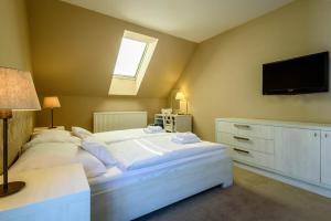 sypialnia z dużym białym łóżkiem i telewizorem z płaskim ekranem w obiekcie Penzión Central Park w Żylinie