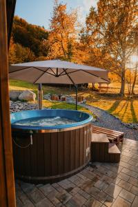 a hot tub with an umbrella and a bench at Lunor House in Izvoare