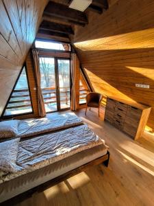 a bedroom in a log cabin with a bed and a chair at Lunor House in Izvoare +38 photos