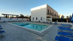 a swimming pool with blue chairs and a building at Casa Vacanza Stella del Mare in San Vito lo Capo
