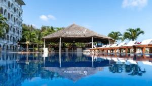 a resort with a swimming pool with a straw umbrella at CityBlue Creekside Hotel & Suites in Mombasa