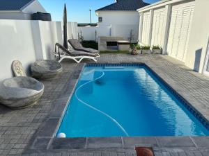 a blue swimming pool in a yard with a patio at Seascape in Dwarskersbos