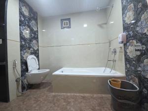 a bathroom with a toilet and a tub and a sink at The Wayside Inn in Matheran