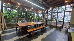 a table and benches in a room with windows at 青禾溫泉家民宿 in Jiaoxi