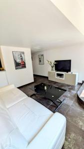 a living room with a white couch and a tv at Cannes Guest House in Cannes
