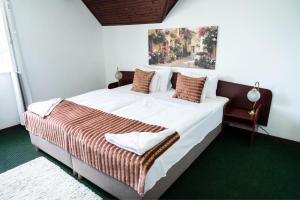 a bedroom with a large bed with a painting on the wall at Bagoly Fogadó in Gyömrő