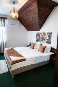 a bedroom with a large bed with a wooden ceiling at Bagoly Fogadó in Gyömrő