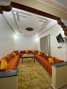 a living room with orange couches and yellow pillows at Comfortable Luxury House in Merzouga
