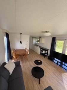 a living room with a couch and a table at Prachtig chalet in Koudum