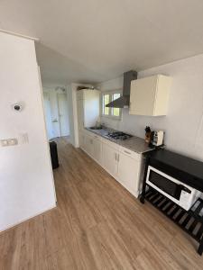 a kitchen with white cabinets and a wooden floor at Prachtig chalet in Koudum +2 photos