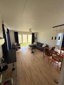 a living room with a couch and a table at Prachtig chalet in Koudum