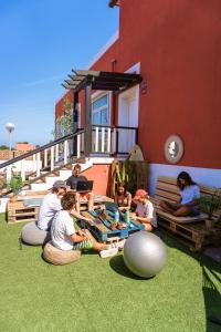 a group of people sitting on the grass outside of a house at Banama Surfhouse - Coliving Coworking & Yoga in Corralejo