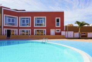 a villa with a swimming pool in front of a building at Banama Surfhouse - Coliving Coworking & Yoga in Corralejo