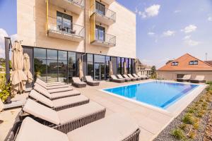 a swimming pool with chaise lounge chairs next to a building at Montello Hotel in Balatonfüred