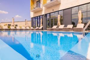 a swimming pool with chairs and a building at Montello Hotel in Balatonfüred +5 photos