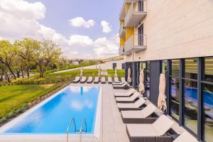 a swimming pool with lounge chairs next to a building at Montello Hotel in Balatonfüred