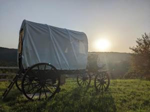 a covered carriage in a field with the sun in the background at La Calèche Western in Lafarre