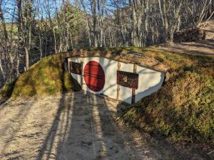 a dirt road with a wall in the middle of a forest at La Maison de Hobbit in Lafarre