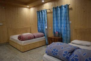 two beds in a room with blue curtains at Devdaar Cottage Gangotri in Gangotri +55 photos