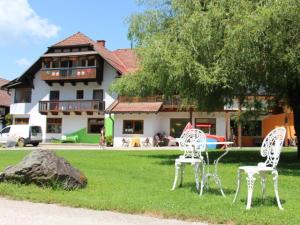 two white chairs sitting in the grass in front of a house at Familienparadies Reichenhauser in Keutschach am See