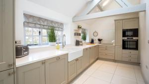 a large kitchen with white cabinets and a window at Garden Cottage in Chipping Campden