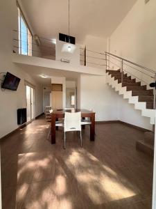 a living room with a table and chairs and stairs at Complejo del jaguel Cabaña Antuan Aires del bosque in Santa Teresita