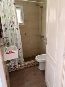 a bathroom with a toilet sink and a shower curtain at Complejo del jaguel Cabaña Antuan Aires del bosque in Santa Teresita +5 photos