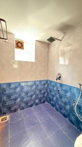 a bathroom with blue tiled walls and a shower at Riverside By GikiJoy in Agarvado