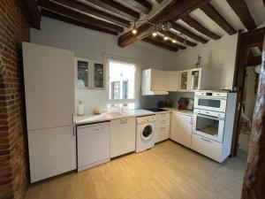 a kitchen with white appliances and a brick wall at Gite CARAMELLE Piscine intérieure privée chauffee toute l annee et spa St Martin in Saint-Martin-lʼHortier