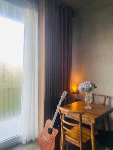 a wooden table with a guitar sitting next to a window at Viora Lodge in Nuwara Eliya