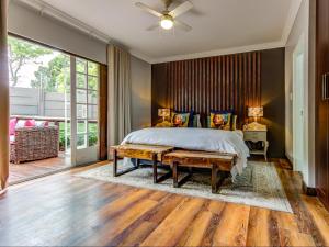a bedroom with a bed and a ceiling fan at Wild Tree Lodge in Benoni