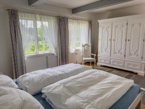 a bedroom with two beds and a chair and windows at Mühlenhof, Keitum auf Sylt in Sylt