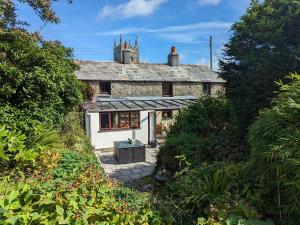 an old stone house with a greenhouse in front of it at Trehaverock Cottage in Port Isaac