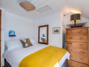 a bedroom with a bed with a yellow blanket and a dresser at Trehaverock Cottage in Port Isaac