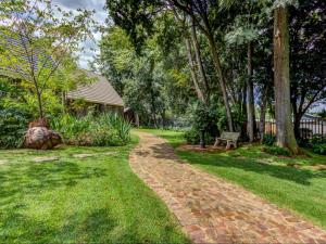 a brick path in a yard with a bench at Wild Tree Lodge in Benoni +12 photos