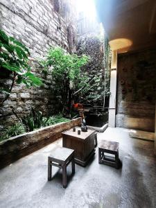 a room with a table and benches and a stone wall at Maison MAY Đà Lạt in Da Lat