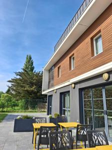 a group of yellow tables and chairs in front of a building at Brit Hotel Vannes - Theix Golfe du Morbihan in Theix