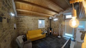 a living room with a yellow couch and a stone wall at Casa ArTè in Modica