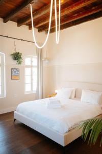 ein Schlafzimmer mit einem weißen Bett und einem Kronleuchter in der Unterkunft Mila - Boutique Hotel in Haifa