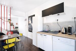 a kitchen with white cabinets and a table with yellow chairs at La Maison Créative in La Madeleine