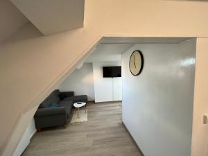 a living room with a couch and a clock on the wall at Spacieux studio in Montlhéry