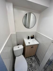 a white bathroom with a toilet and a mirror at Spacieux studio in Montlhéry
