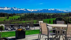 a patio with a table and chairs and mountains at Góralska Dolina II Jacuzzi & Sauna in Zakopane