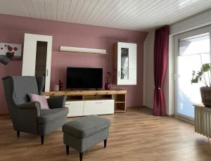 a living room with a television and a chair at snevernheimat, Ferienwohnung in Schneverdingen