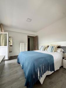 a bedroom with a large bed with a blue blanket at el AS del Puntal in Villaviciosa