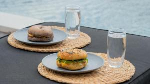 two plates of food on a table with glasses of water at Villa Uma Sawan By 25Hours Hospitality in Bedahulu