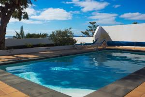 a swimming pool with chairs next to a house at Villa Corona in Puerto del Carmen
