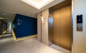 an elevator in a building with a blue wall at Adena Hotel in Busan