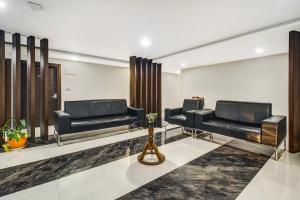 a waiting room with two black leather couches at Hotel O D Suites in Hyderabad